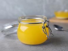 Glass jar of Ghee butter on grey table, closeup