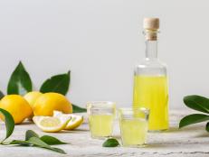 Limoncello in small glasses and bottle  - italian lemon liqueur, fresh italian lemons. Light background, copy space.
