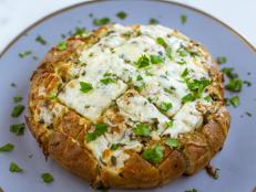 For this special occasion bread, Ree doctors up a store-bought loaf of focaccia, scoring and stuffing it with a mix of cheeses, sage and red pepper flakes. This works with any kind of bread, such as ciabatta, rustic Italian or French bread. Ree thinks a round loaf makes it look a little more celebratory.