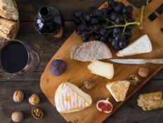 Käseplatte mit Camenbert, Walnusskäse, Gorgonzola, Taleggio, dazu Rotwein, Weintrauben, Feigen, Nüsse und Baguette