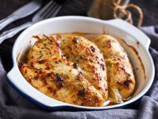 close-up of oven baked spicy juicy chicken breasts in a baking dish on a dark wooden table