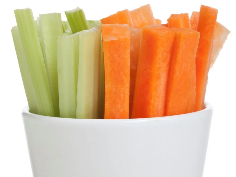 Bowl of carrot and celery sticks isolated on a white background.