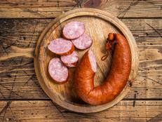 Bavarian Smoked sausage on a wooden board with herbs. White wooden background. Top view.