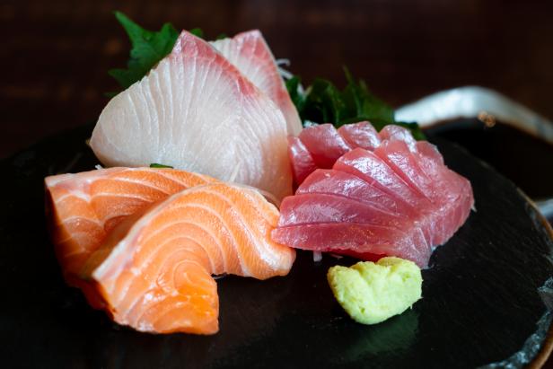 Raw fish Sashimi traditional Japanese food set includes Raw Salmon, Raw Tuna, Raw Yellow Tail (Hamachi) Sliced with sliced radish and vegetable