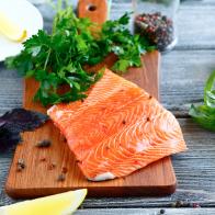 Salmon fillet with parsley, basil and lemon on cutting board, food ingredient