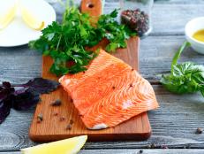 Salmon fillet with parsley, basil and lemon on cutting board, food ingredient