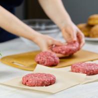 Woman's hand forming a beef meat for a hamburger party. Portioning ground meat. Homemade burgers. Making food at home. close up