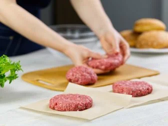 Woman's hand forming a beef meat for a hamburger party. Portioning ground meat. Homemade burgers. Making food at home. close up