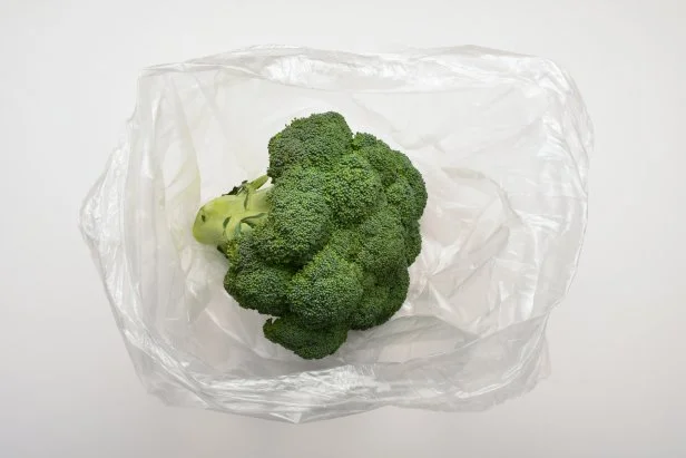 Fresh broccoli in a plastic shopping bag on the white background