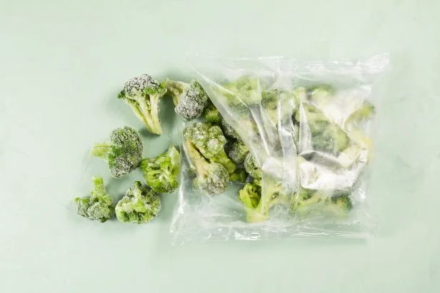 Frozen vegetables on light background with copy space. Broccoli in transparent bag. Proper defrosting of vegetables. Stock up on vitamins for winter.