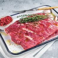 Piece of raw beef brisket with herbs and spices ready for bbq smoker. Gray background. Top view.