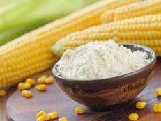 Corn flour in a bowl and corn cob on the table