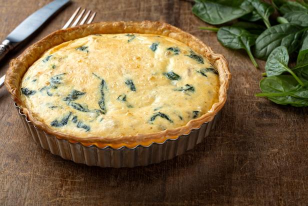 Freshly backed spinach quiche, just from the oven on wooden background