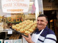 Yonah Schimmel standing outside his Lower East Side Knishery, proudly displaying his famous  knishes.