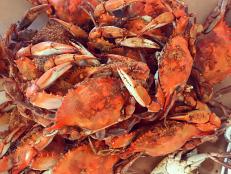 Maryland Steamed crabs covered in spices and served on a table covered in brown paper. Blue crabs cooked with spicy seasoning.