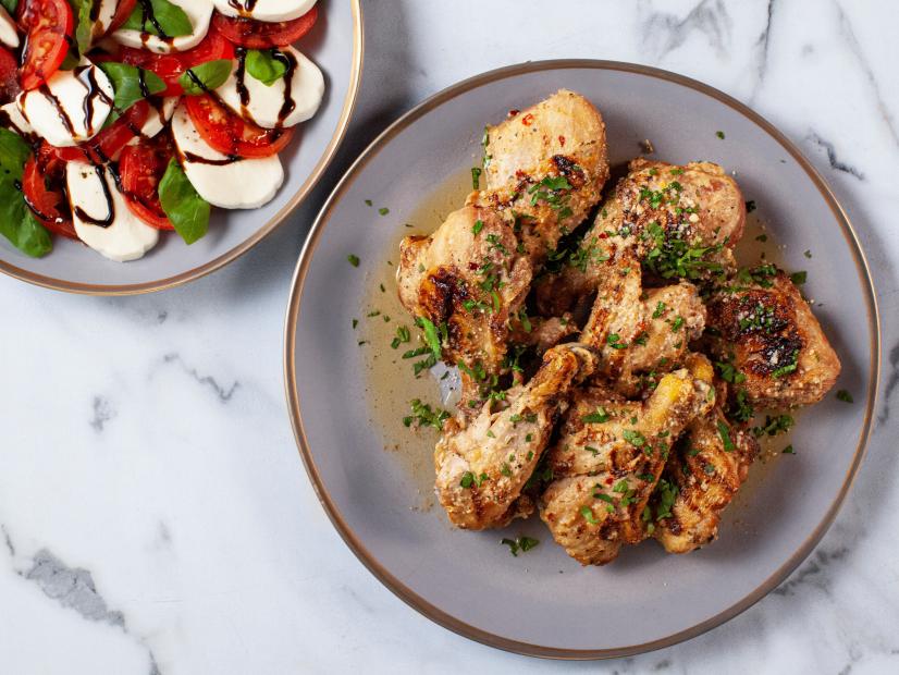 Close-up of Butterflied Garlic Parmesan Drumsticks with Caprese Salad, as seen on The Pioneer Woman, season 34.