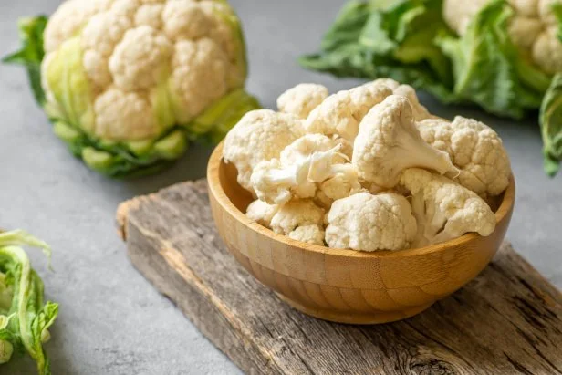 Fresh raw organic cauliflower with leaves on rustic background, uncooked vegetable