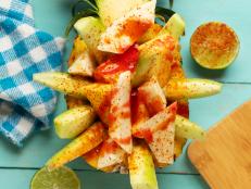 Fresh cucumber, jicama and pineapple with chili powder and chamoy sauce on turquoise background. Mexican snack