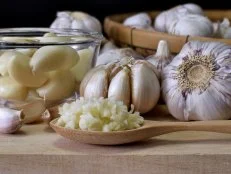 Close-up shot of minced garlic in wooden spoon placed on wooden chopping board In the kitchen prepared for food ingredients.