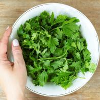 Women hand put plate of green herbal salad on old wooden table. Healthy eating dieting concept. Top view. Flat lay. Close up. Selective soft focus. Shallow depth of field. Text copy space.