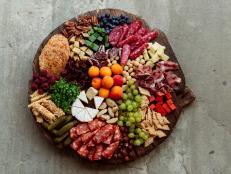 Summert gathering plate - wooden board with various appetizer snacks - cheese and nuts, fruits and meats for big group of people