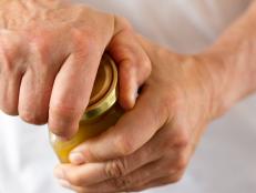 Close-up shot of strong male hands twisting open a stubborn jar lid.