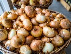 A scene from a farmstand on Cape Cod MA highlighting a full bucket of fresh Visalia onions for sale.