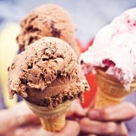 Girl holding three ice cream cones with chocolate and strawberry creams.