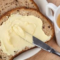 Bread and butter. A knife spreading butter on bread