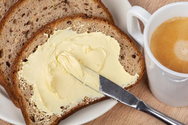 Bread and butter. A knife spreading butter on bread