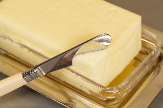 Knife and pack of butter in a butter dish made of metal and glass
