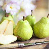 Green pears on wooden board with knife.