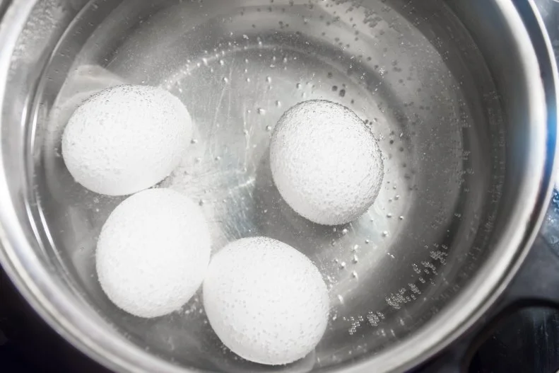 Cooking white chicken eggs in a saucepan