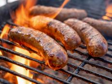 Hot Delicious Bratwurst or Brats on a fiery grill almost ready to eat