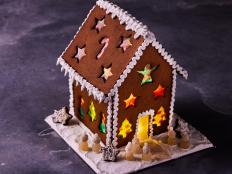 Brighten up your holiday table with this showstopping centerpiece dessert. The dough for the gingerbread house is both sturdy and delicious, and the recipe makes enough for the house and additional gingerbread people for decorating. The candy windows create a stunning stained-glass effect and add a pop of color, especially when lit from within by a flameless LED tealight or LED fairy lights (turn off the lights when not in use).