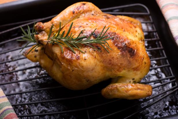 A roasted cornish game hen fresh out of the oven and garnished with a sprig of rosemary.