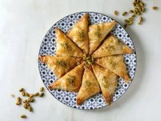 Homemade Turkish traditional dessert baklava with pistachio served on ornate plate over white marble background. Flat lay, space