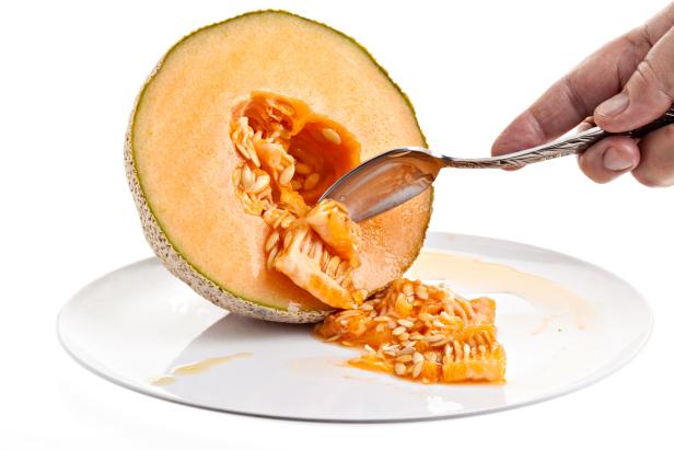 Cleaning a cantaloupe on a white background.