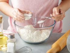 Women adds the baking powder into the glass bowl with flour. Step by step recipe of homemade mexican flatbread tortilla.