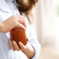 Cropped image of a woman trying to open a jar in the kitchen