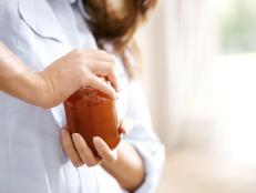 Cropped image of a woman trying to open a jar in the kitchen