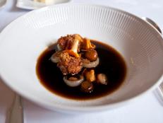 Mushrooms in Bouillon with onion and sweetbreads kept in white plate.
