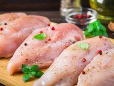 Raw chicken fillets on a cutting board against the background of a wooden table. Meat ingredients for cooking