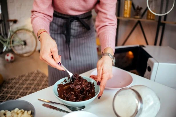 Woman prepares chocolate to fill donuts
