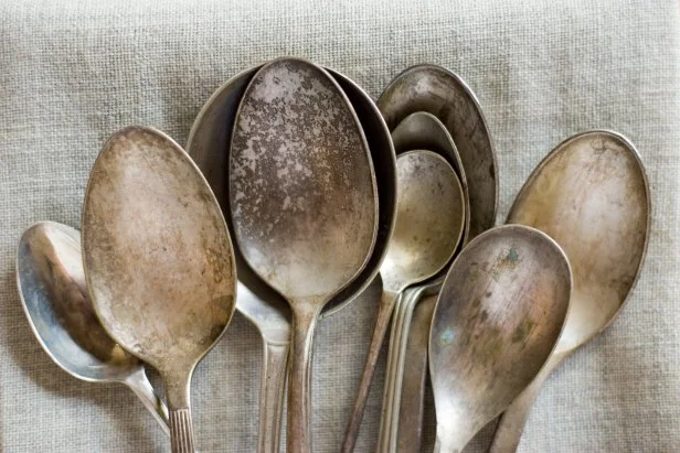 Many used and old spoons on a natural linen cloth.