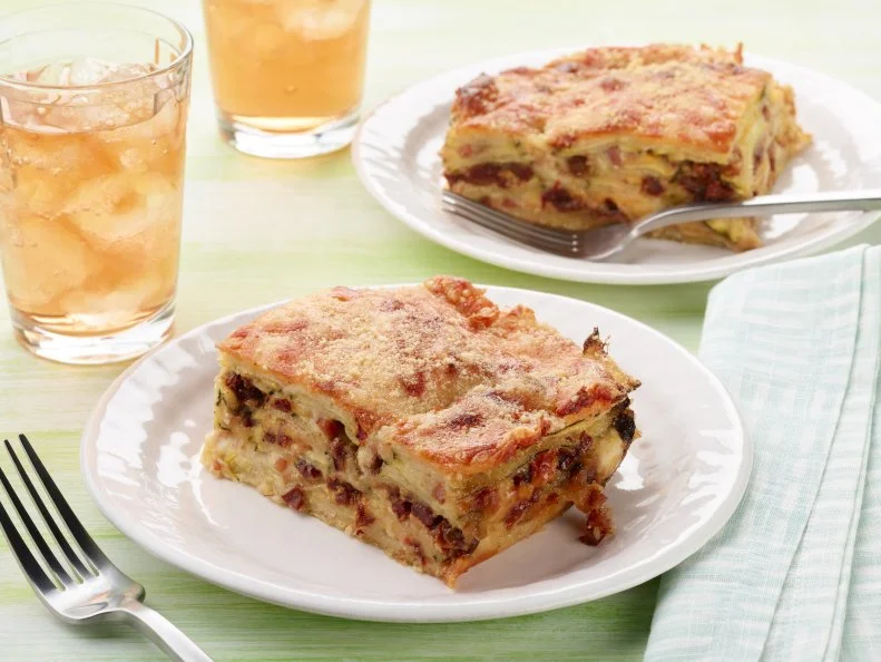 Food Network Kitchen’s Cheesy Zucchini Bake with Pancetta and Sun-Dried Tomatoes as seen on Food Network.