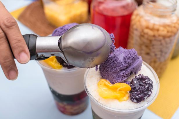 Adding a scoop of ube ice cream to top a recipe of Halo-halo, a popular cold dessert in the Philippines.