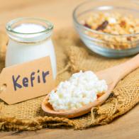 Kefir grains in wooden spoon in front of cups of Kefir Yogurt Parfaits. Kefir is one of the best health foods available providing powerful probiotics.
