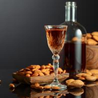 Strong alcoholic Italian liqueur Amaretto with almonds nuts on a black background.
