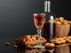 Strong alcoholic Italian liqueur Amaretto with almonds nuts on a black background.